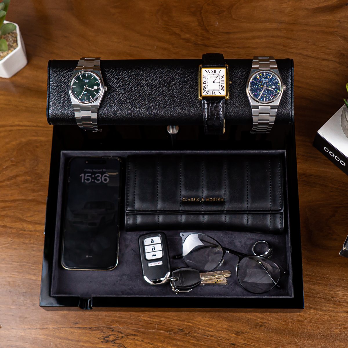Top-down: three watches on the LWR leather pillow, phone, wallet, car key, glasses and a ring in the suede tray